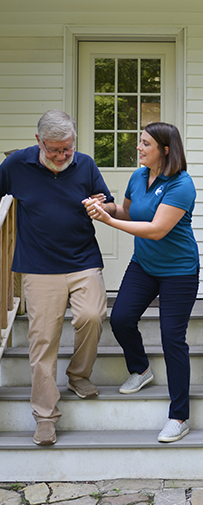 A Visiting Angels caregiver adjusting safety measures in a home, such as handrails and non-slip mats, to prevent falls for elderly residents.