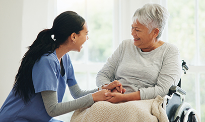 A Visiting Angels caregiver offering comfort and support to an elderly patient receiving palliative care, emphasizing compassion in a serene home setting.